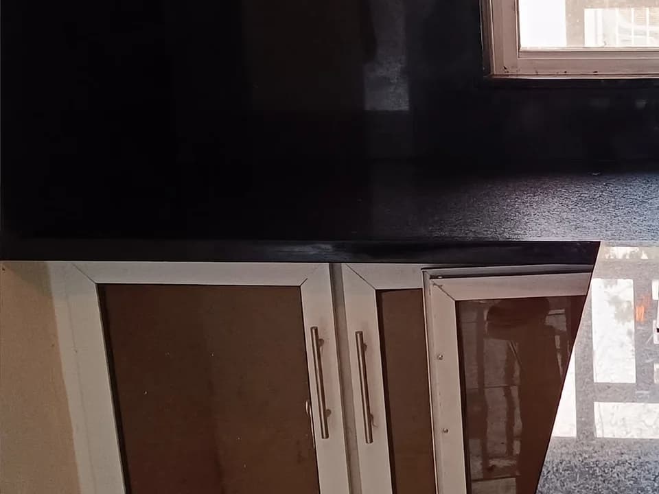 Encimera de granito negro instalada sobre gabinetes de cocina.